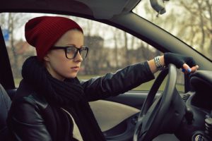 Teenager in glasses and a beanie driving a car - Riddle & Brantley