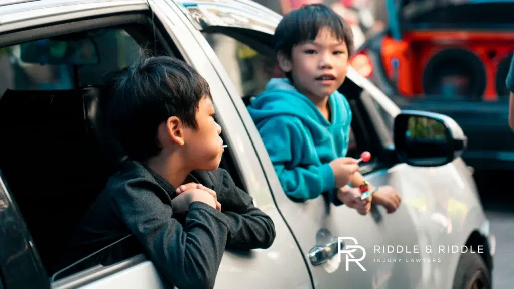 two children hanging out of a car window