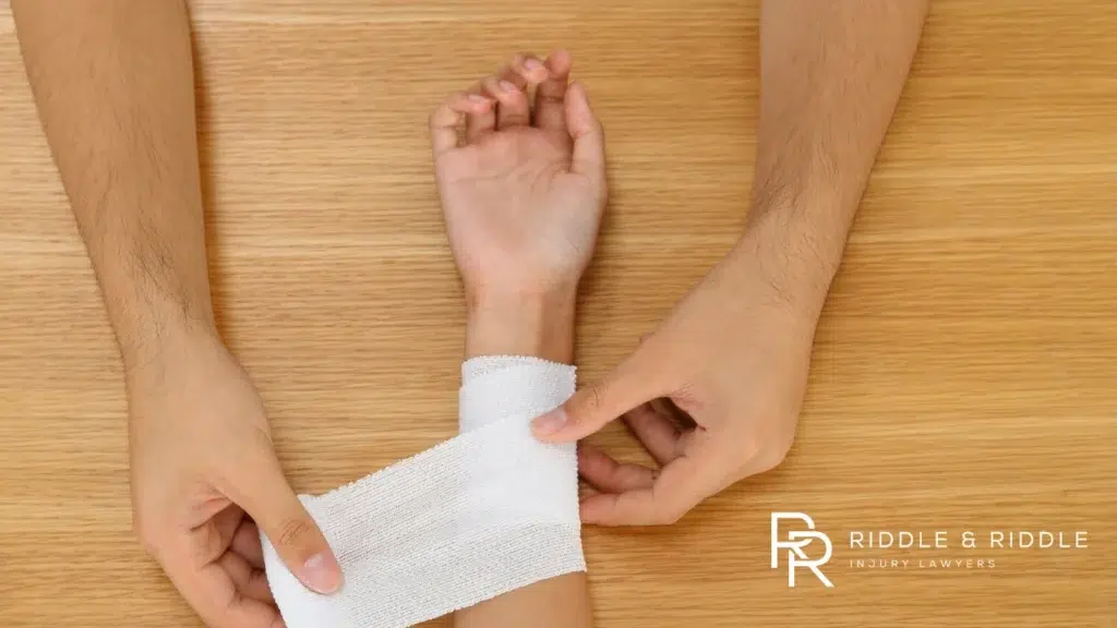 Healthcare worker wraps a person's injured wrist with a white gauze bandage