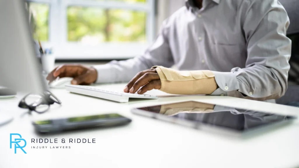Man sitting at a computer with an injured hand