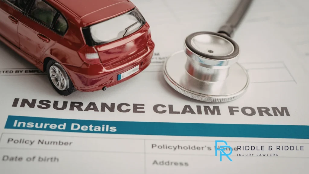 Stethoscope and a red toy car rest on an INSURANCE CLAIM FORM on a desk