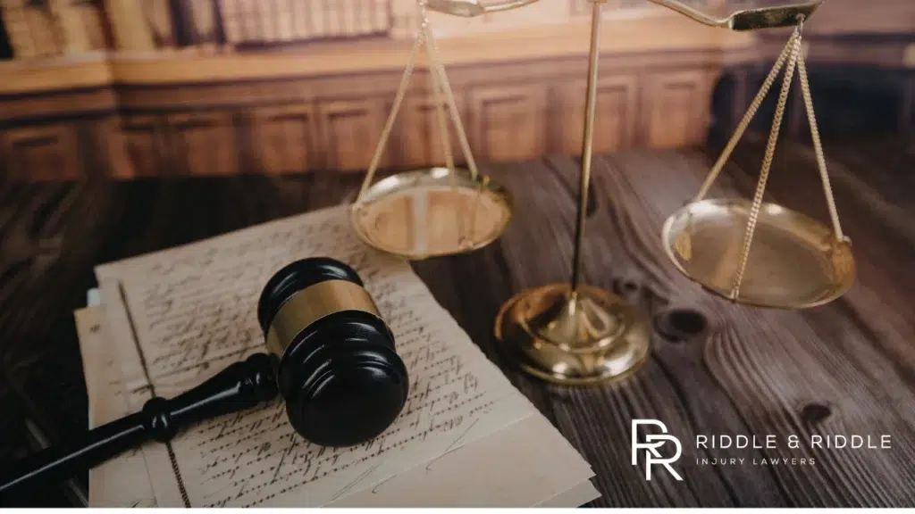 A judge's gavel and the brass scales of justice resting on a dark wooden table