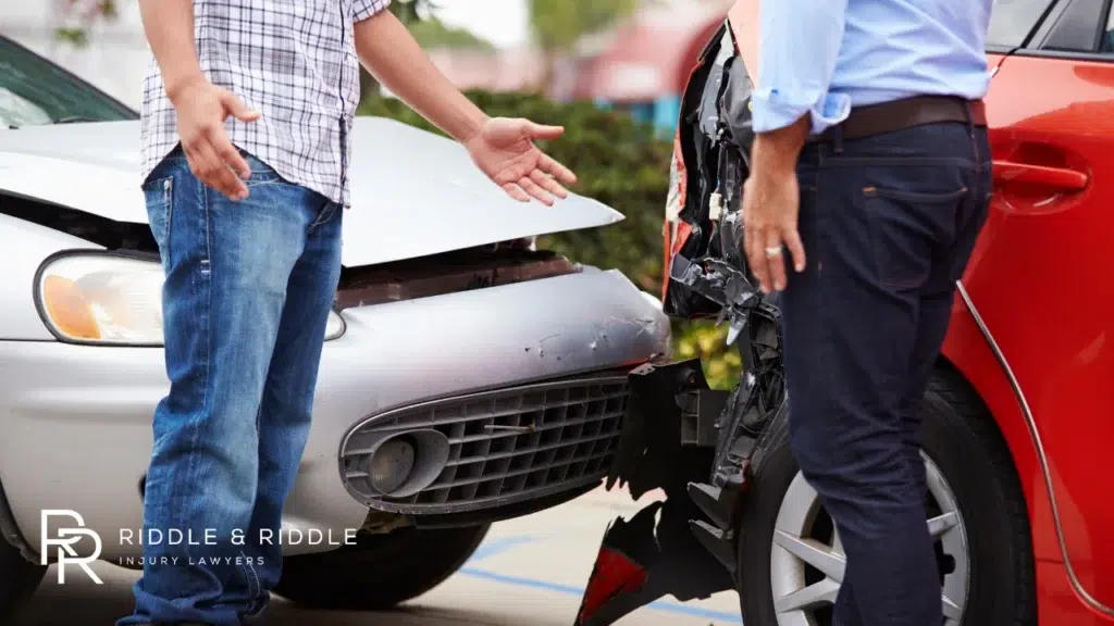 women-standing-next-to-a-silver-and-dark-car-following-a-rear-end-collision-on-a-street