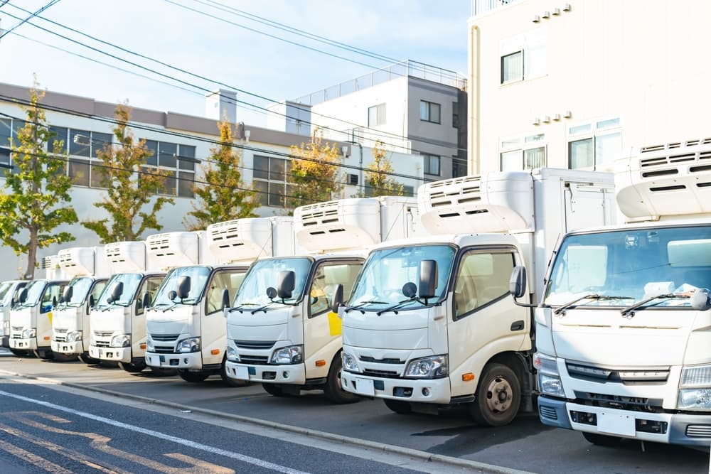 Many trucks lined up in the parking lot of a distribution center.