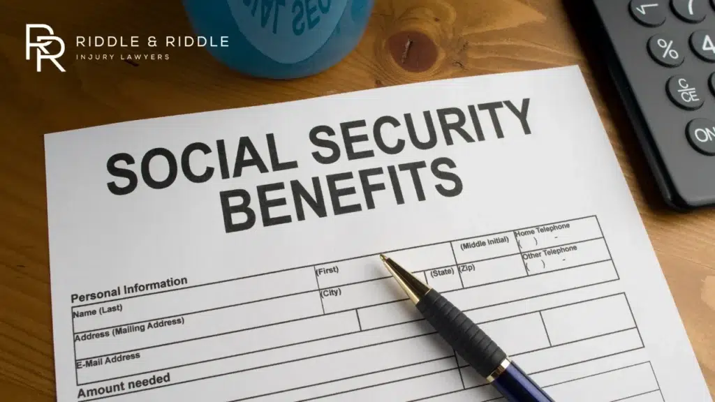 Overhead view of a SOCIAL SECURITY BENEFITS form and a pen on a wooden desk