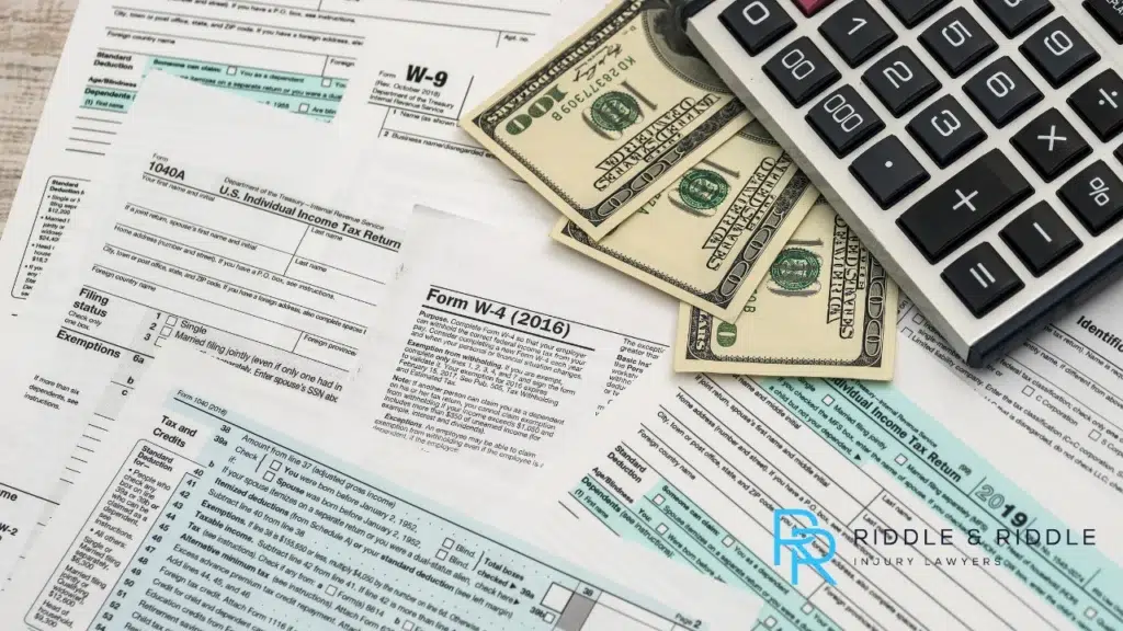 Tax documents with a calculator and hundred dollar bills