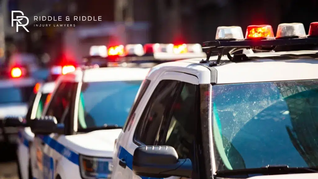 A line of police cars at night with their red and blue emergency lights flashing