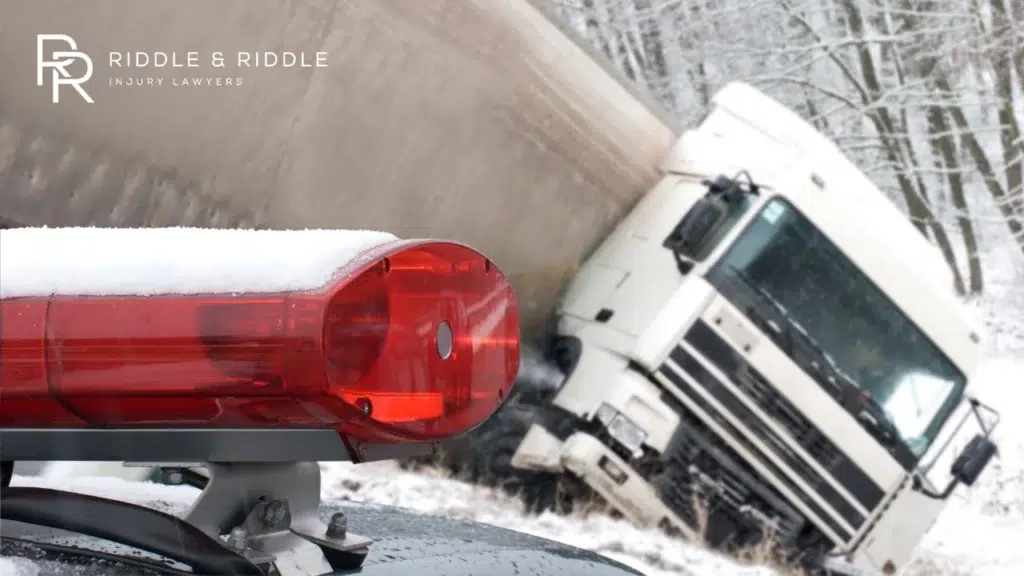 Large semi-truck jackknifed on a snowy road with emergency lights in the foreground