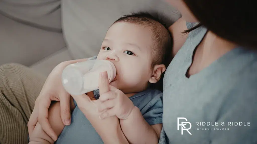 Close-up of a baby being fed from a bottle by a parent