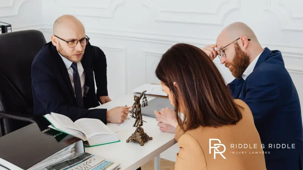 Two men in suits discuss legal matters with a woman at a desk