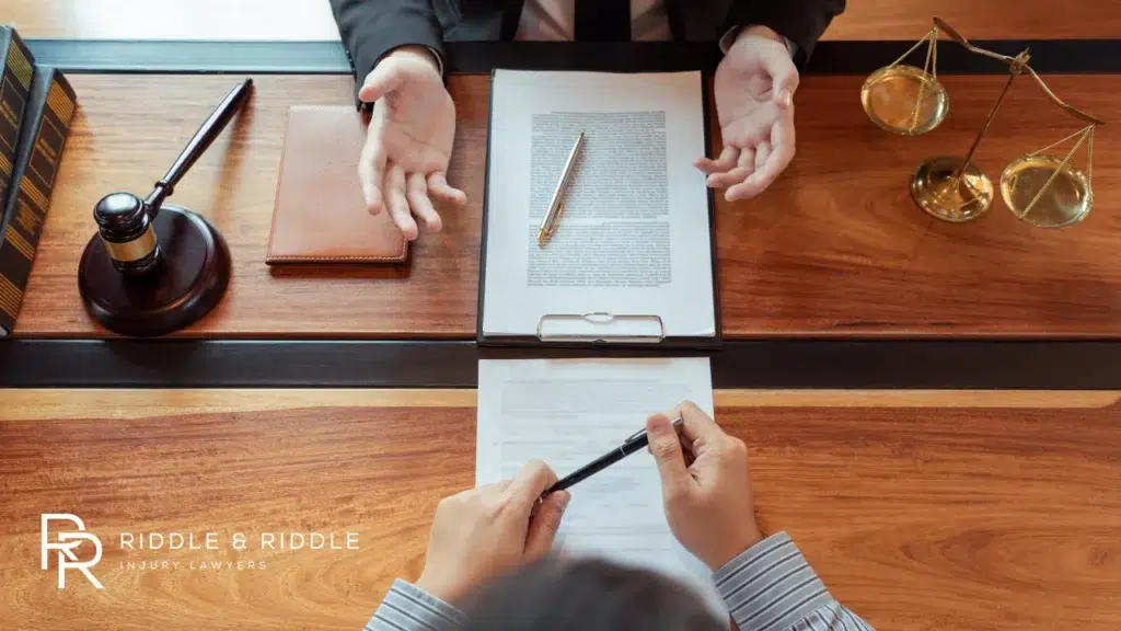 Overhead view of hands signing a document on a wooden desk with a gavel