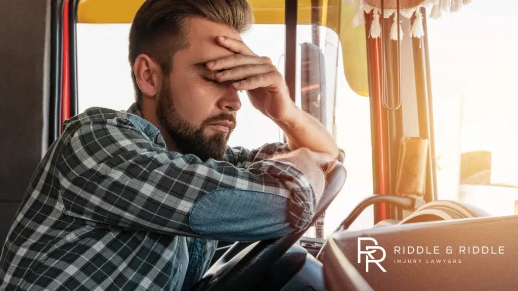 man in a plaid shirt leans his head on his hand in frustration while sitting in a truck
