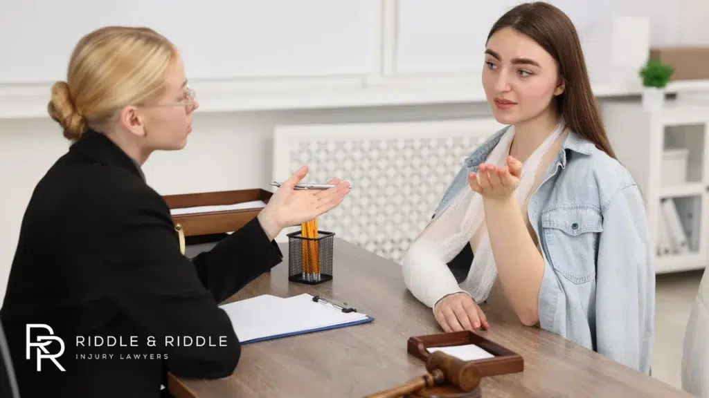 Blonde lawyer in glasses talks with a female client at a desk in a bright office