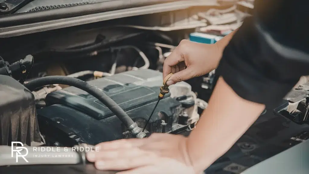 Mechanic's hands check the oil dipstick of a car engine in a garage
