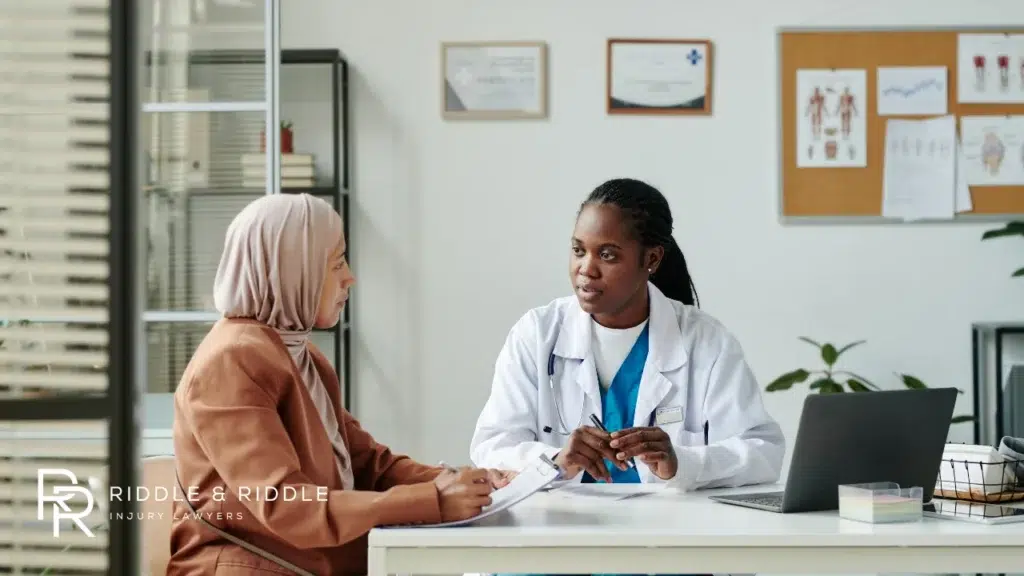 Female doctor in a white coat discusses a medical case with a patient wearing a hijab