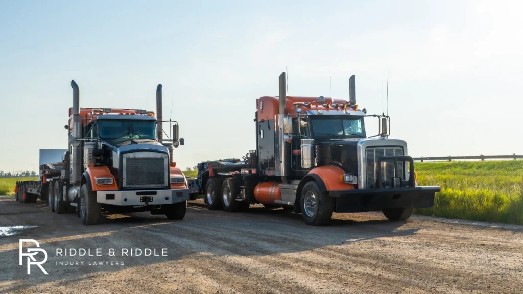 Two large semi-trucks parked side-by-side on a gravel lot under a clear sky