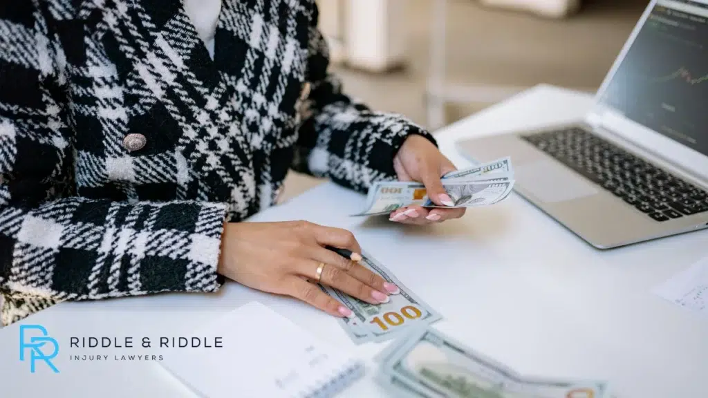 Person counting money sitting on desk