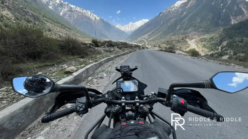 First-person perspective from a motorcycle rider traveling on a scenic mountain road