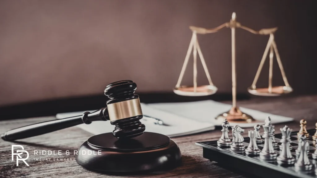 A judge’s gavel, the scales of justice, and a chess set arranged on a wooden table
