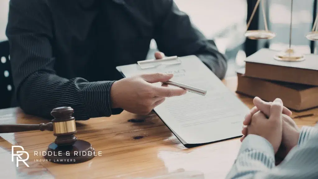 Legal professional points to a document while speaking with a client at a desk