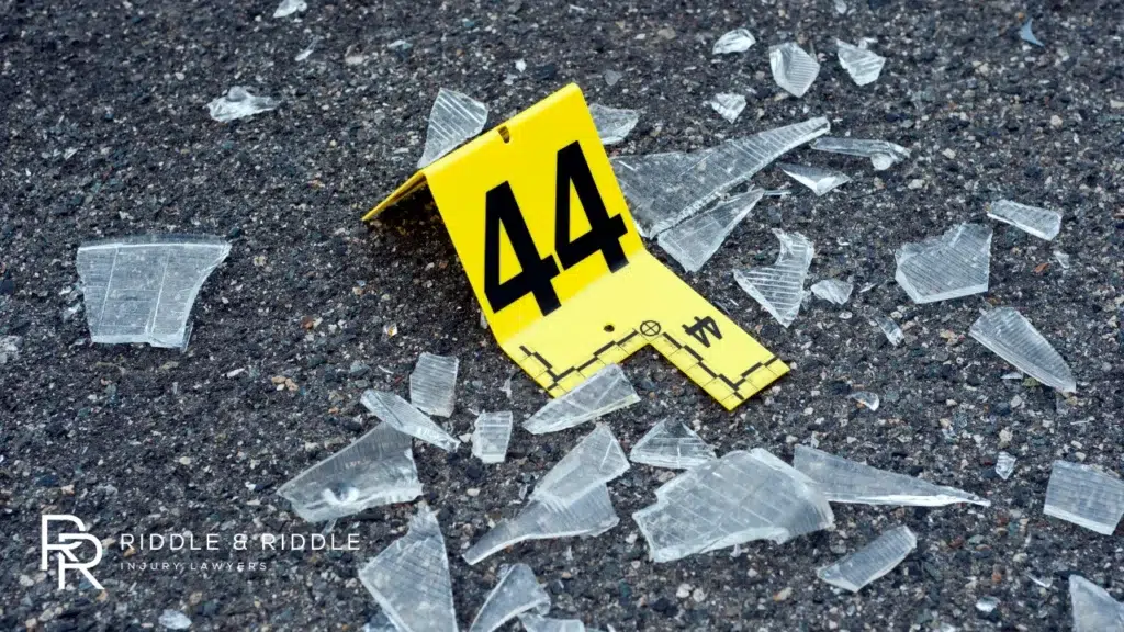Yellow forensic marker with the number 44 sits among shattered glass on asphalt