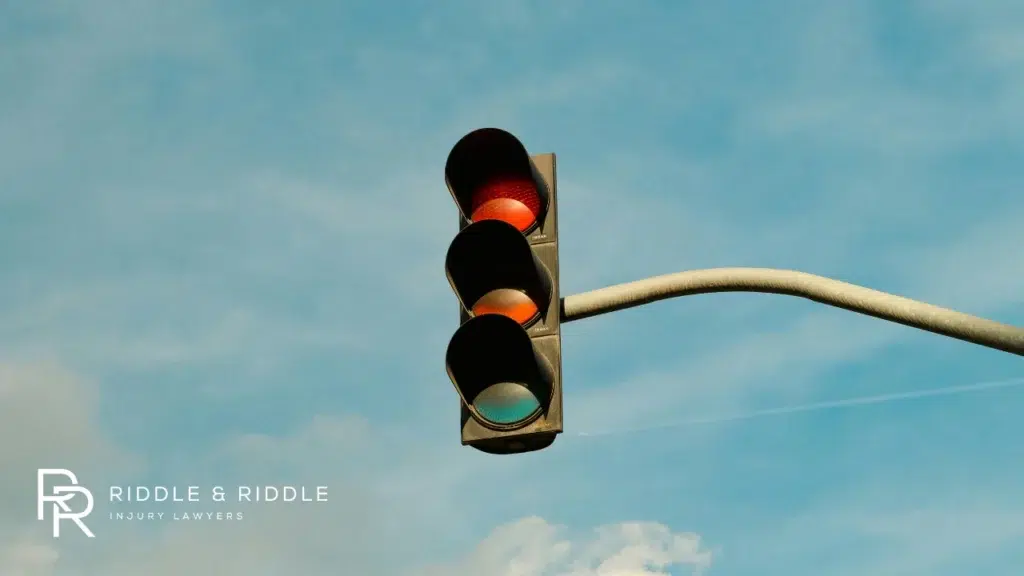 Low-angle shot of a traffic signal showing a solid red light against a blue sky