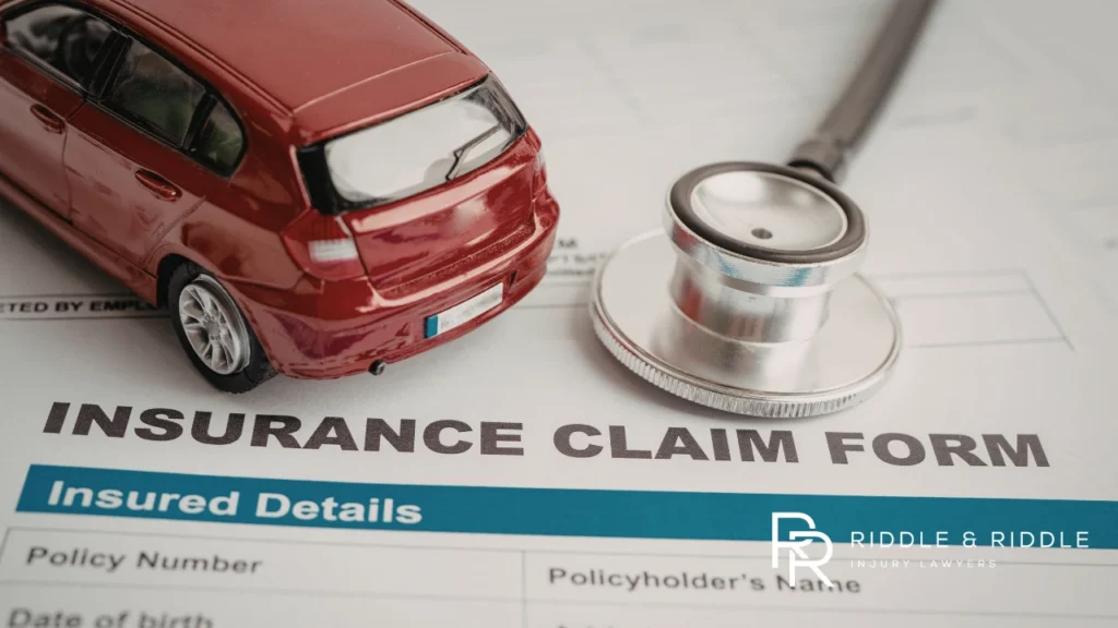 Stethoscope and a red toy car sit on top of an INSURANCE CLAIM FORM