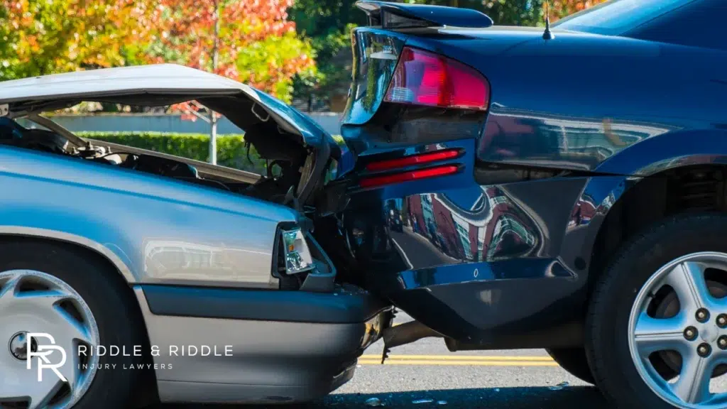 Close-up of a blue car with a severely crushed rear bumper and trunk
