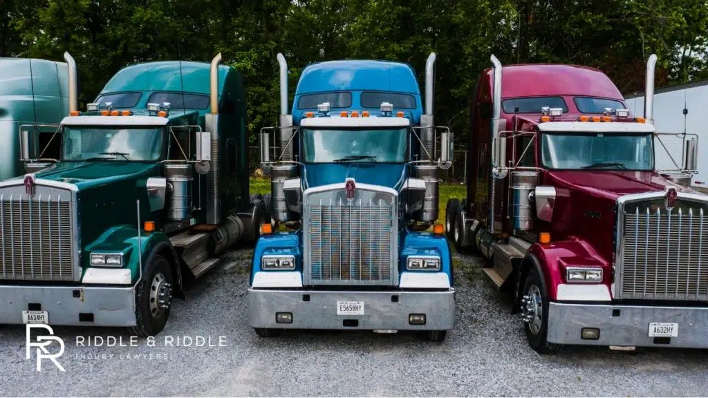 Front view of four large commercial semi-trucks in different colors parked in a row