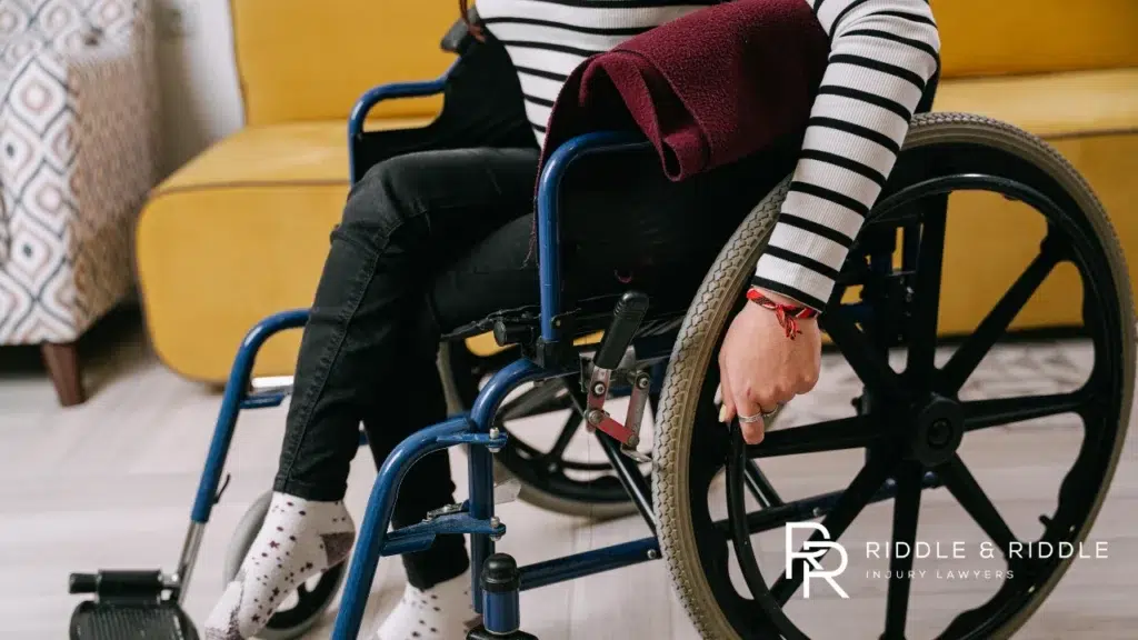 Person wearing a striped shirt sits in a manual wheelchair indoors