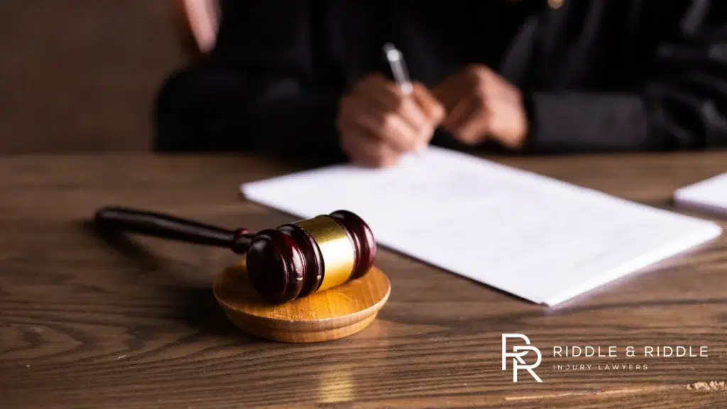 Gavel sits next to a legal document being signed by a person in a dark suit