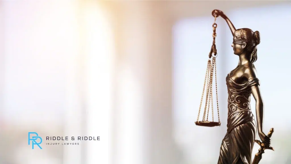 Bronze Lady Justice statue holding scales against a soft, blurred light background