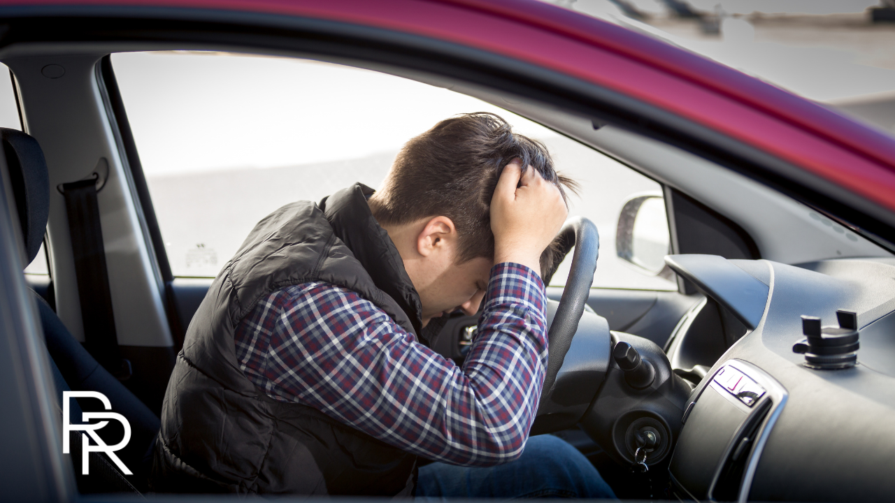 Man close to getting in a car accident leans over the wheel and pulls at his hair in stress