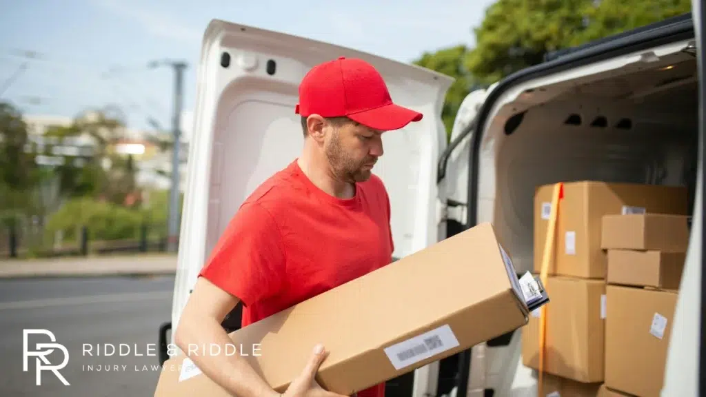 Delivery person in a red shirt and cap unloading a cardboard package
