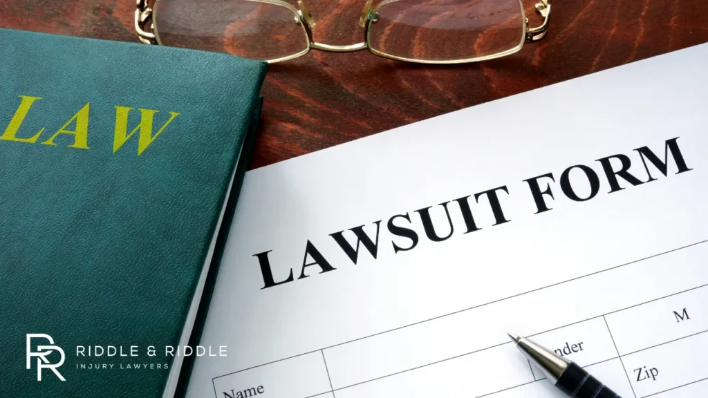 An image showing a Lawsuit form and brown law book with Pen on the table