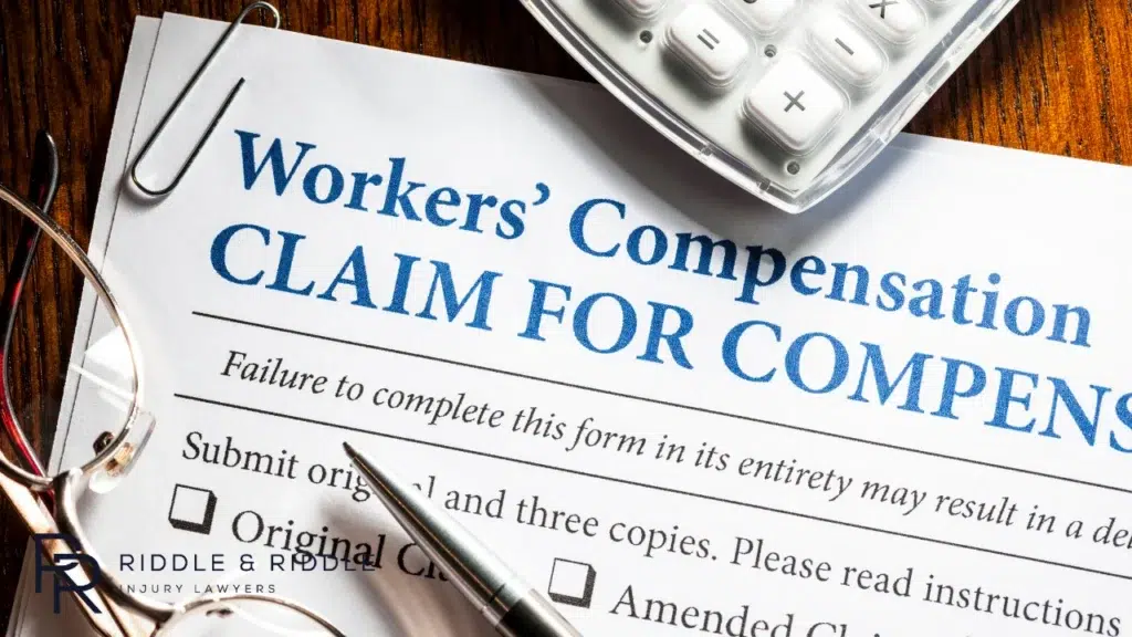 Workers' Compensation claim form on a screen with a pen